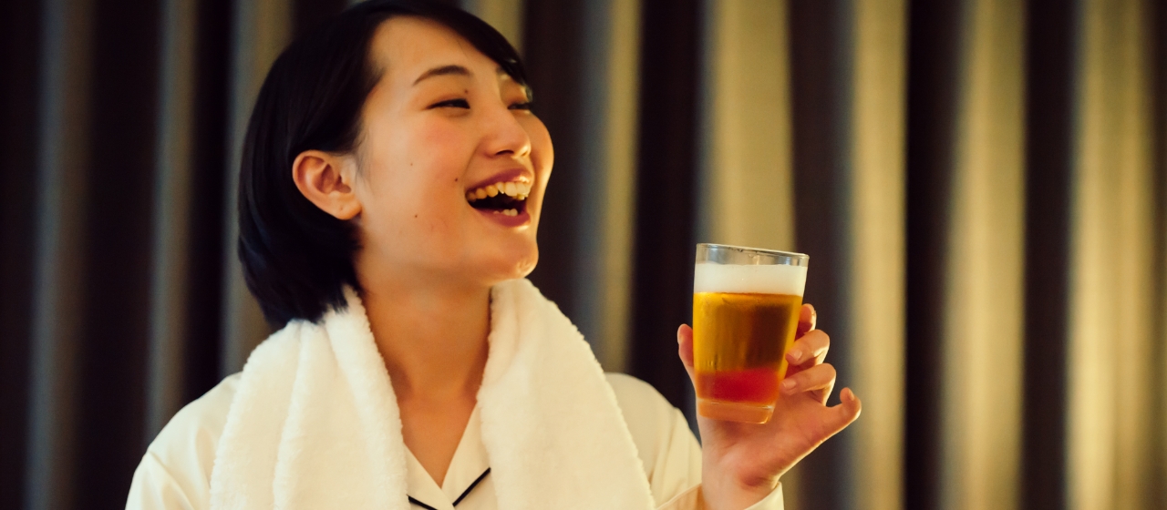 女性がビールを飲んで幸せそうにしている写真